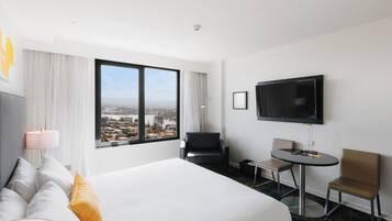 A hotel room with a large bed, a TV, a desk, and a chair.