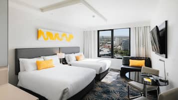 A hotel room with two beds, a sofa, a TV, and a city view.