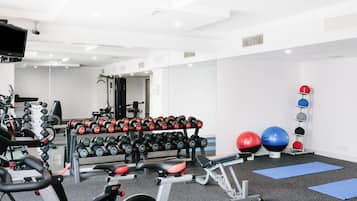 A gym with exercise equipment, including dumbbells, a treadmill, and exercise balls.