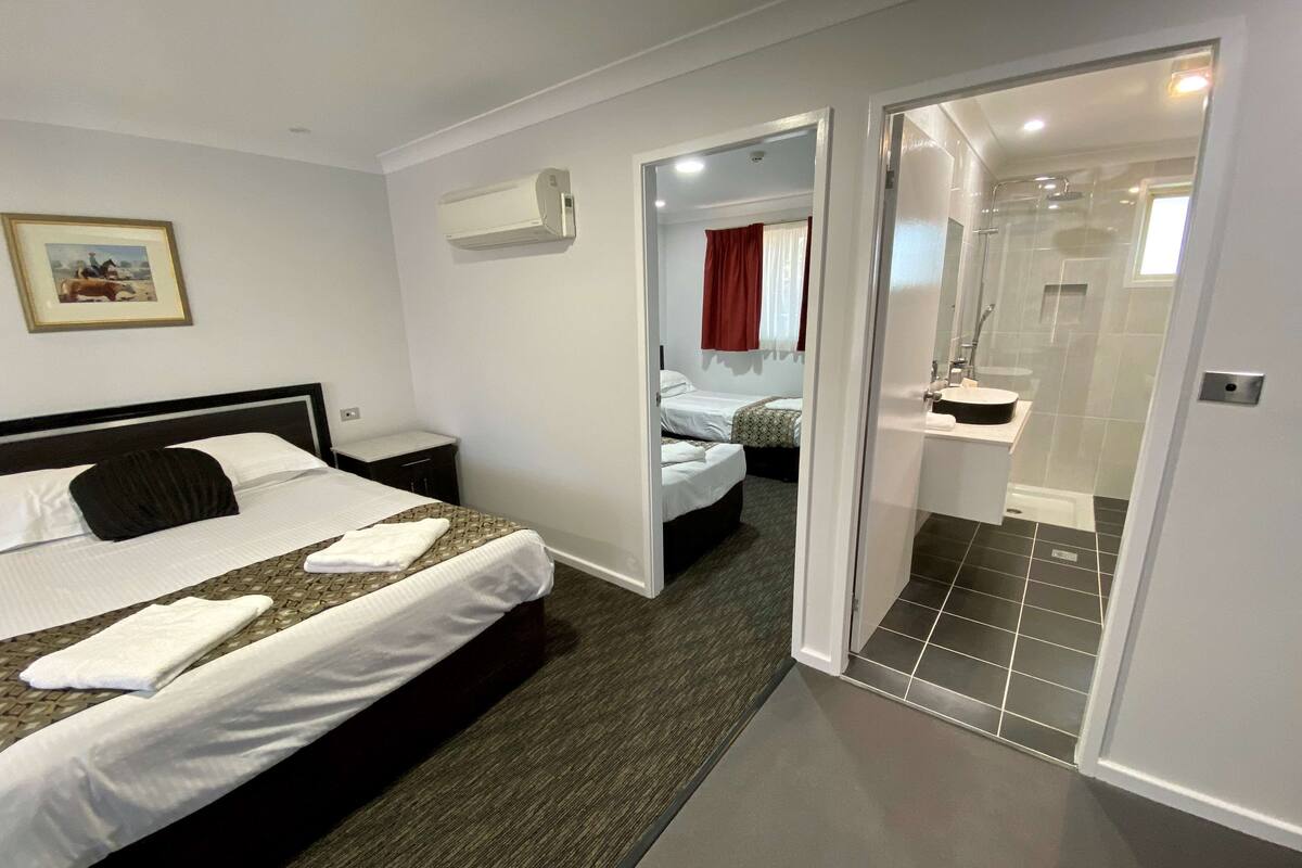 A hotel room with a bed, bedside table, and a bathroom with a shower and sink.