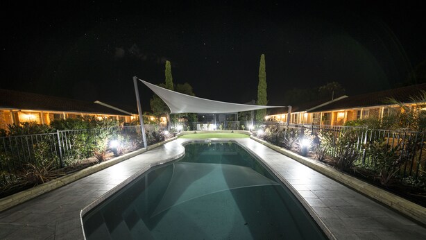 A swimming pool with a white canopy, surrounded by a fence and illuminated by lights. - Best Western Plus All Settlers Motor Inn (South Tamworth)