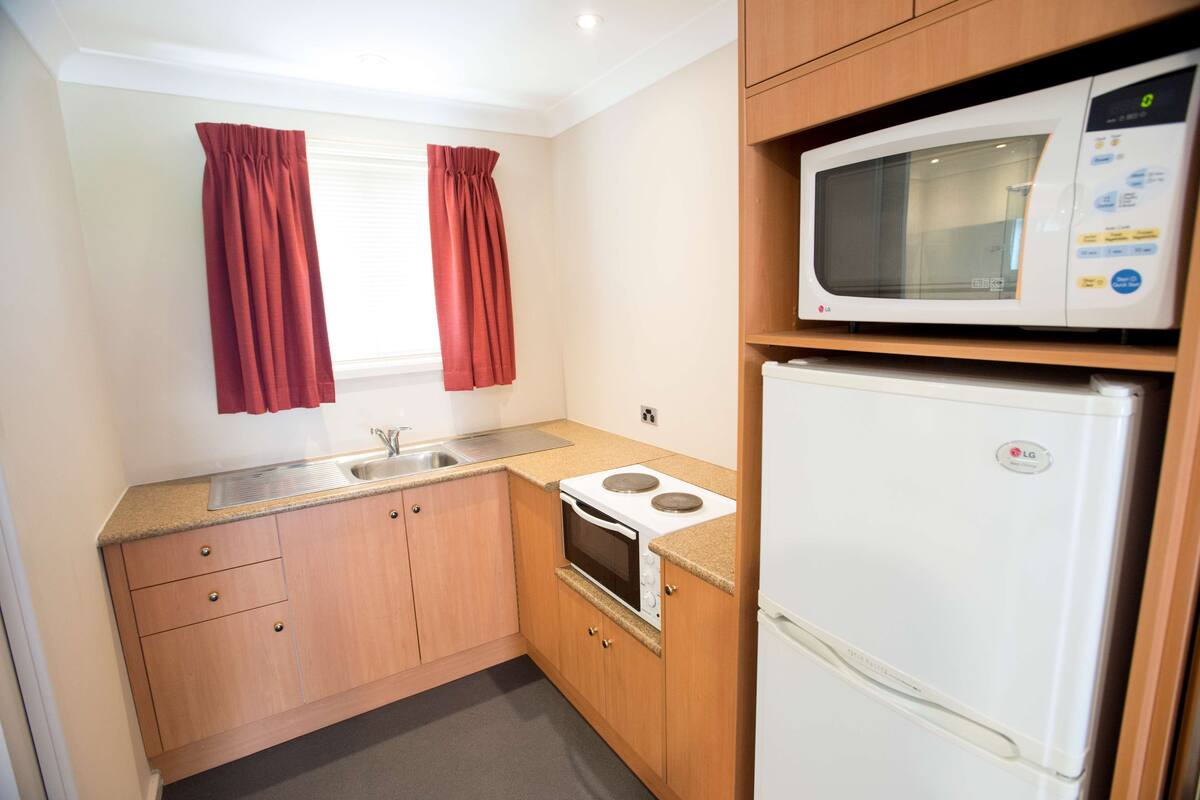 A compact kitchen with a microwave, stove, and sink.