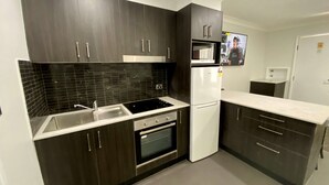 A modern kitchen with dark cabinetry, a stainless steel sink, and a built-in oven. - Best Western Plus All Settlers Motor Inn (South Tamworth)