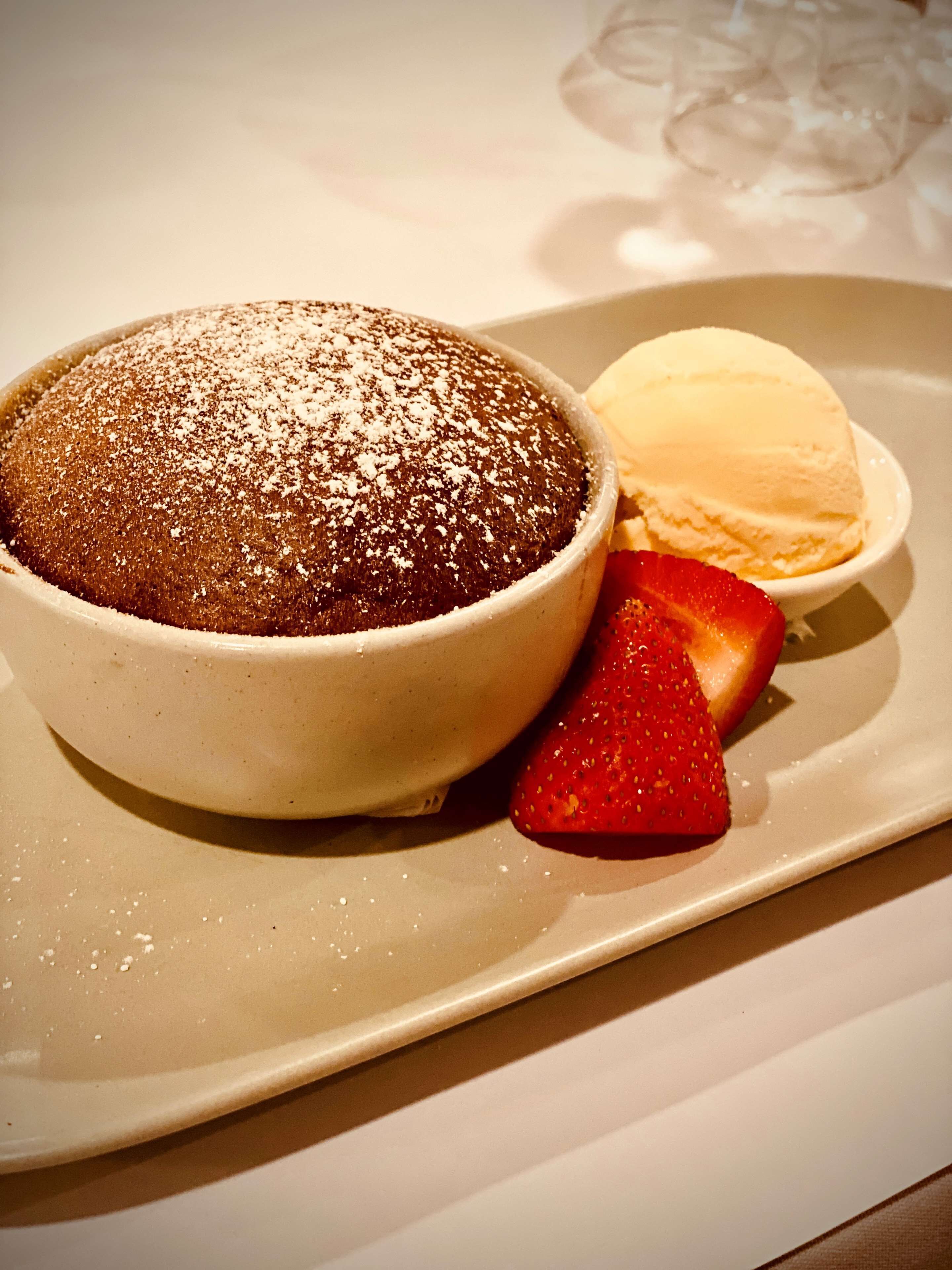 Dessert met een laagje poedersuiker, een bolletje vanille-ijs en een aardbei.