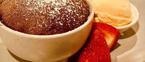 A dessert with a dusting of powdered sugar, a scoop of vanilla ice cream, and a strawberry.