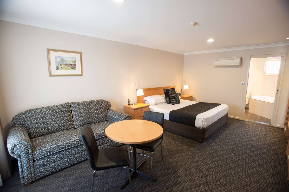 A hotel room with a bed, a sofa, a table, and a chair.