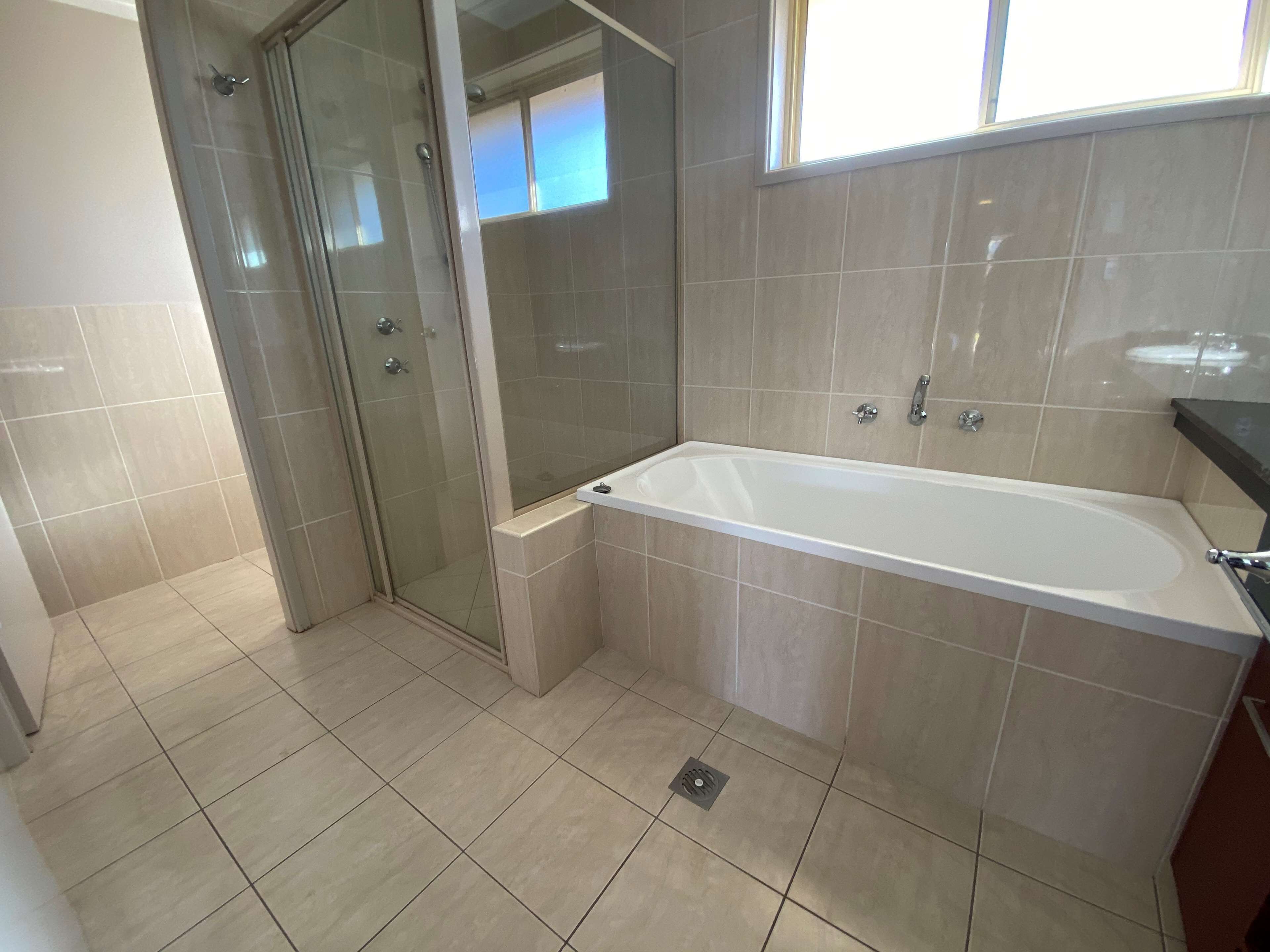 Un baño moderno con ducha de vidrio, bañera independiente y piso de baldosas.