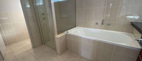 Un baño moderno con ducha de vidrio, bañera independiente y piso de baldosas.