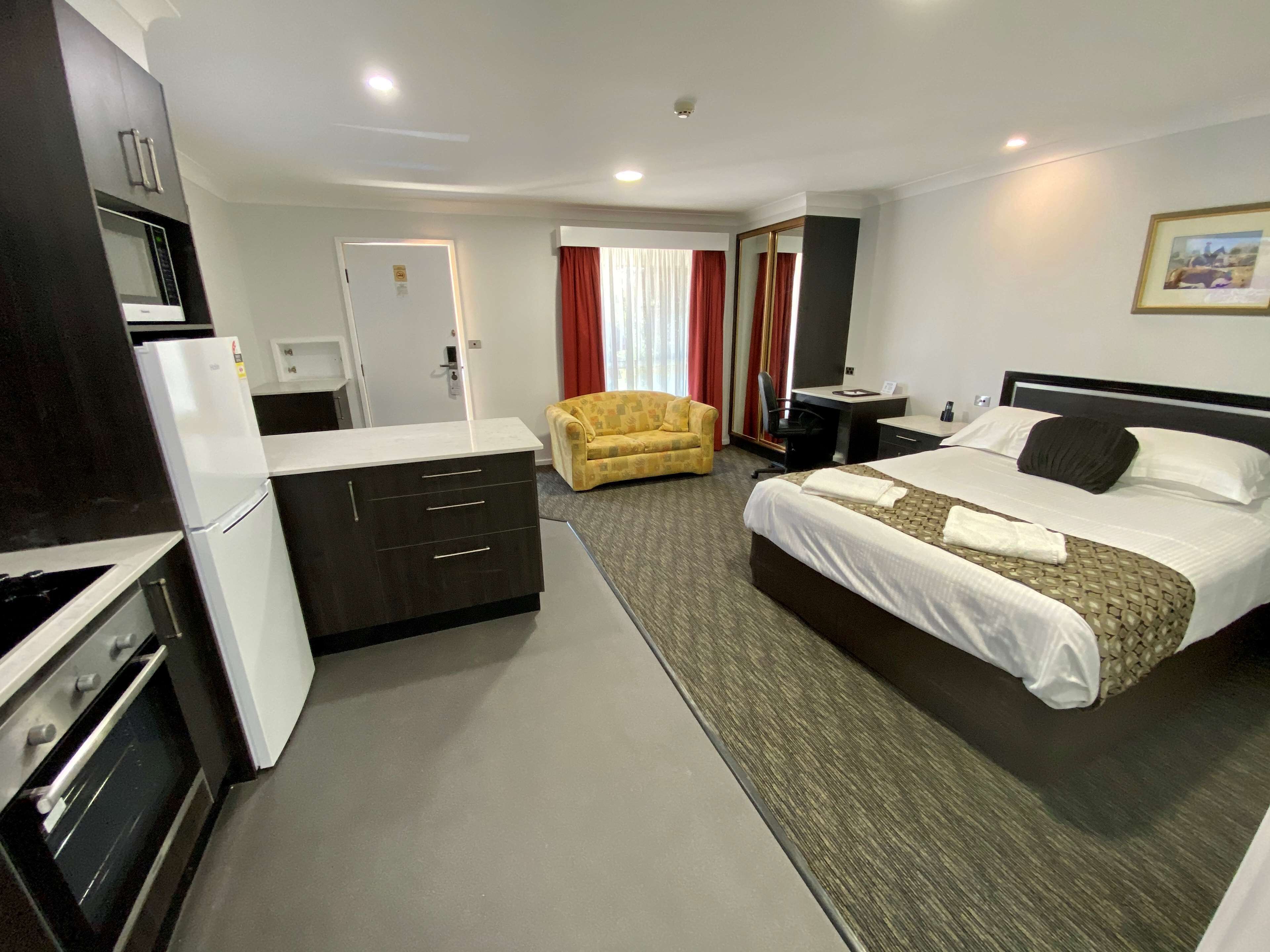 Una habitación de hotel con cama, escritorio, sofá, kitchenette y baño.