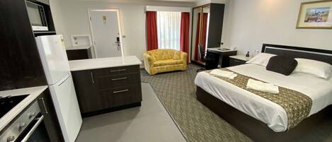 Una habitación de hotel con cama, escritorio, sofá, kitchenette y baño.