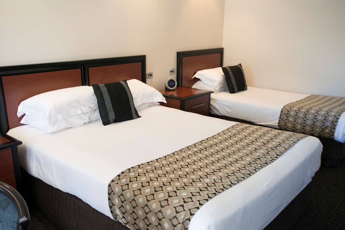 Two single beds with wooden headboards, white bedding, and a patterned throw blanket.