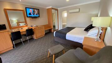 A hotel room with a bed, a desk, a chair, a television, and a mirror.