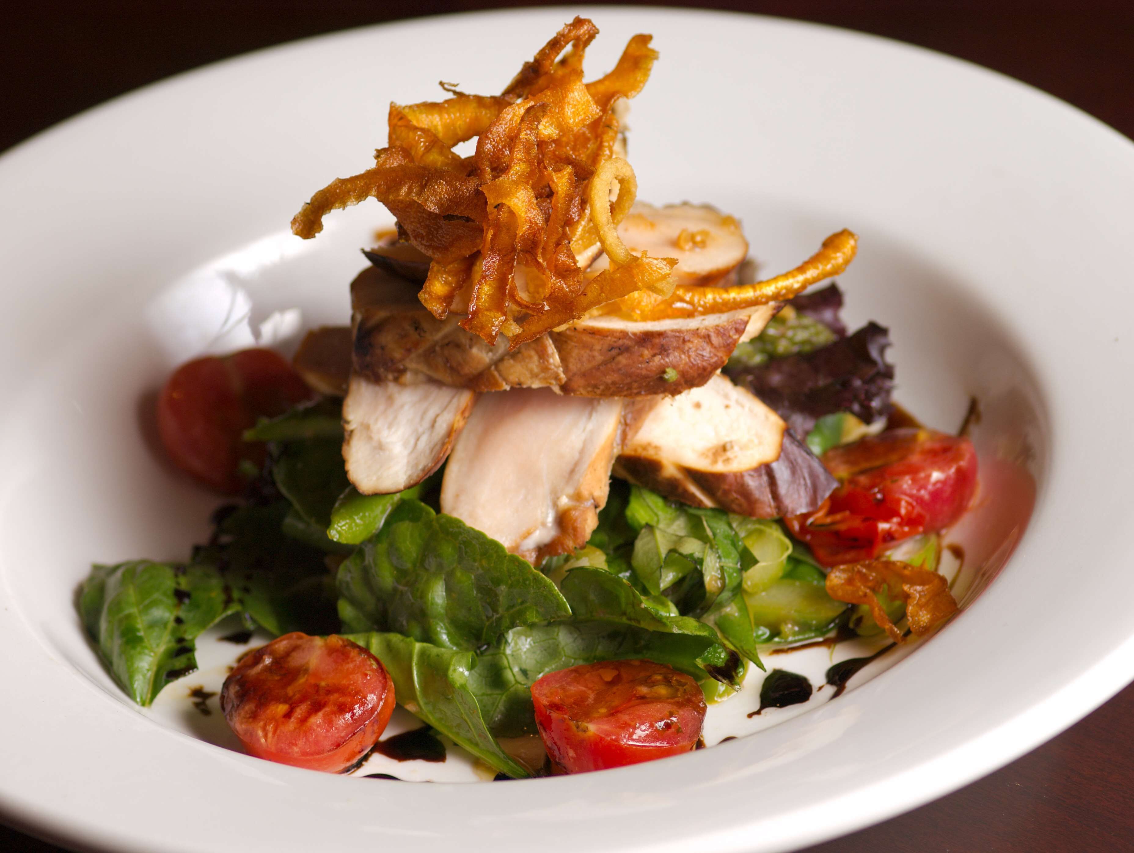 A plate of food with grilled chicken, vegetables, and crispy fried onions.