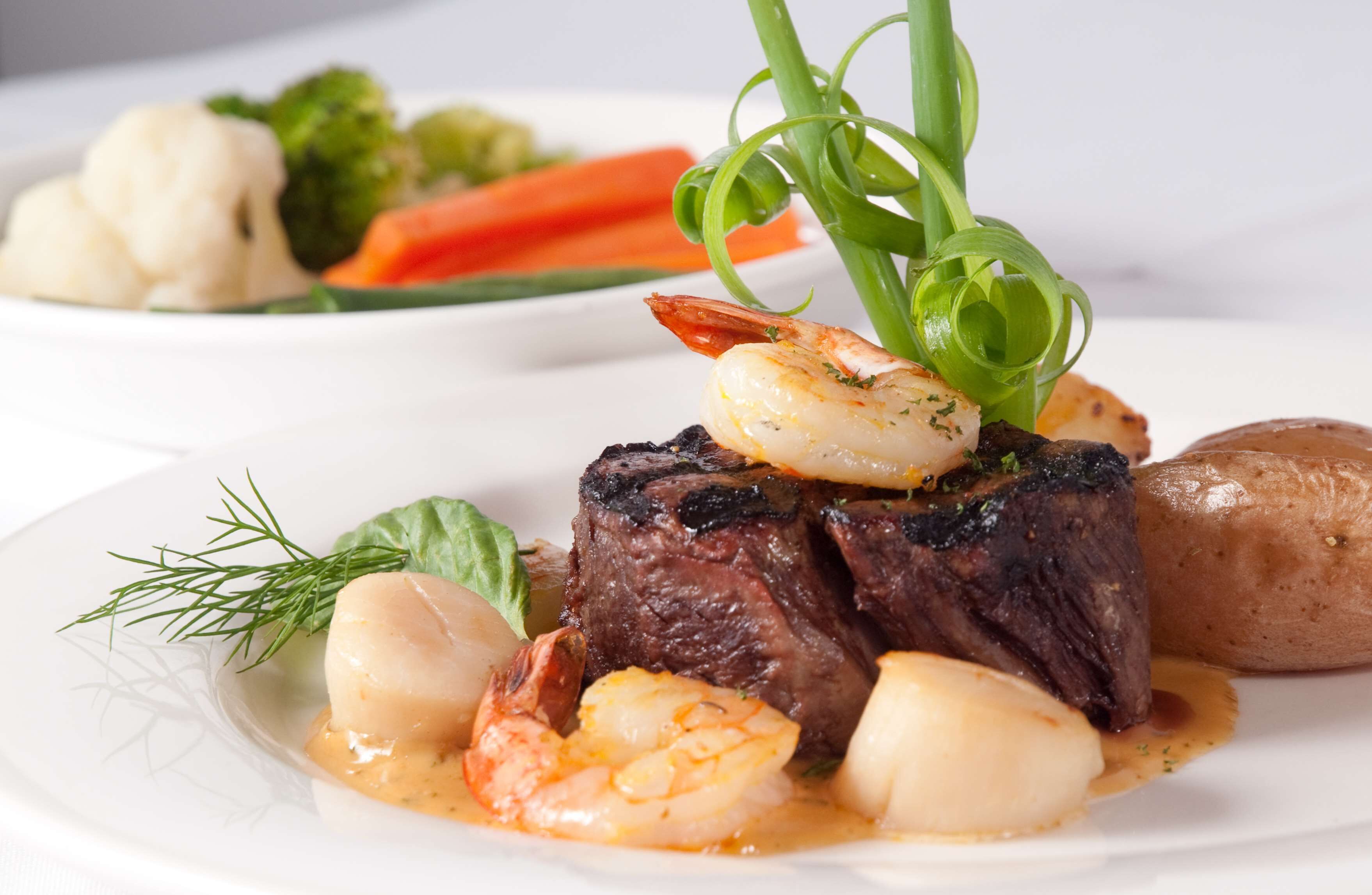 A plate of food with steak, shrimp, and vegetables.