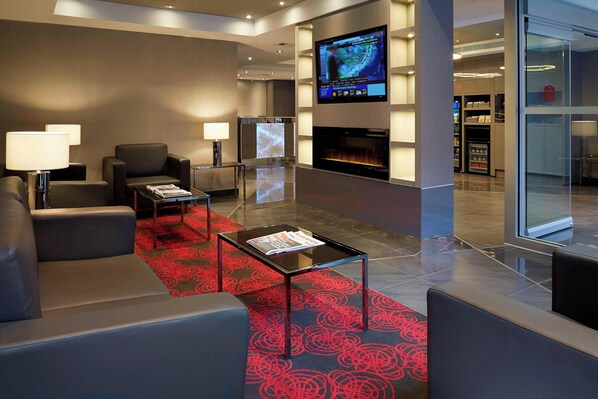 A modern lobby with leather seating, a glass coffee table, a flat-screen TV, and a fireplace. - Residence Inn by Marriott Montreal Downtown (Montreal)