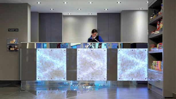 Un área de recepción con diseño moderno, que incluye un mostrador de recepción, una pantalla digital y una máquina expendedora.