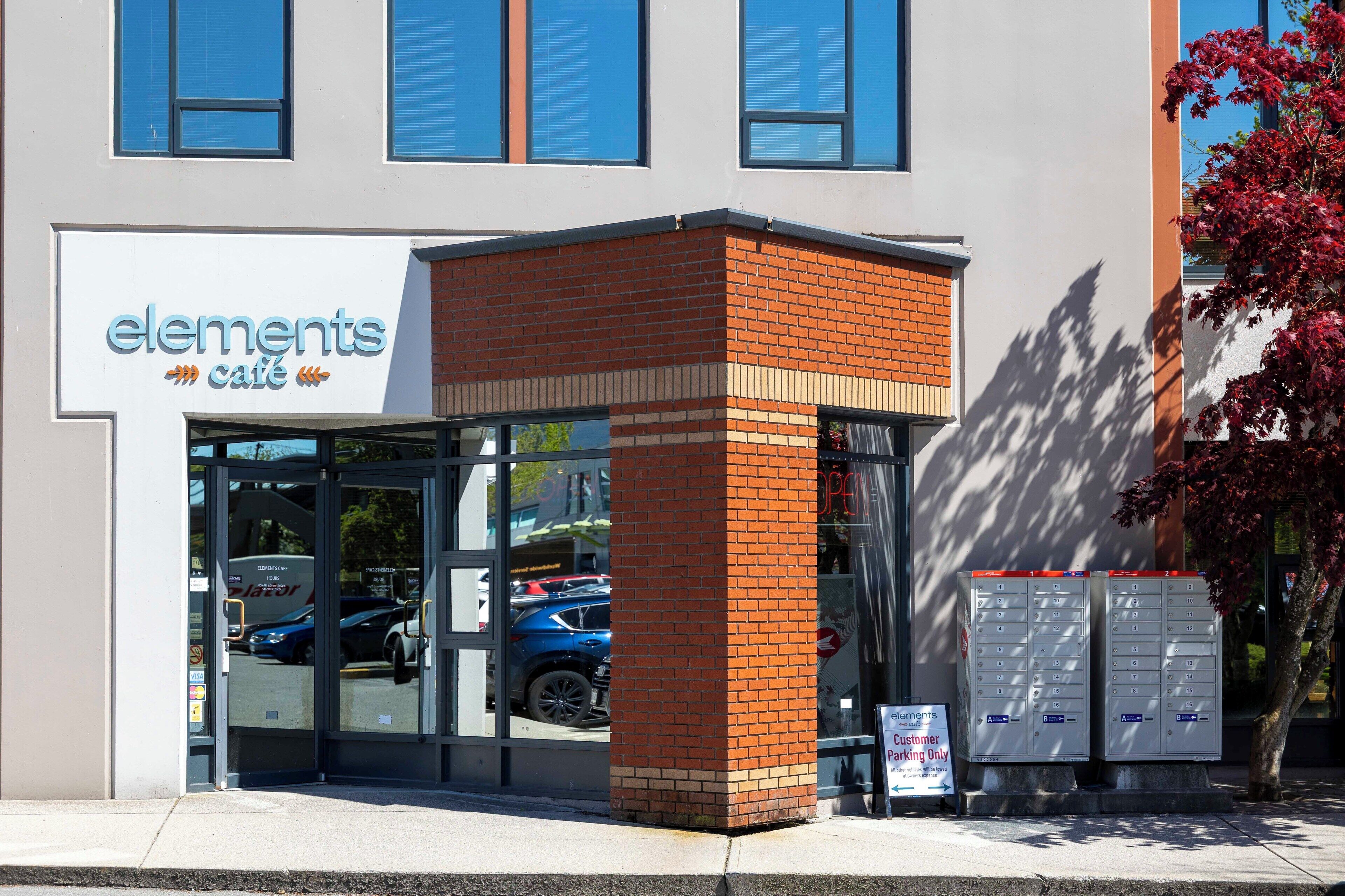 A building with a sign reading "elements cafe" and a parking sign indicating customer parking only.