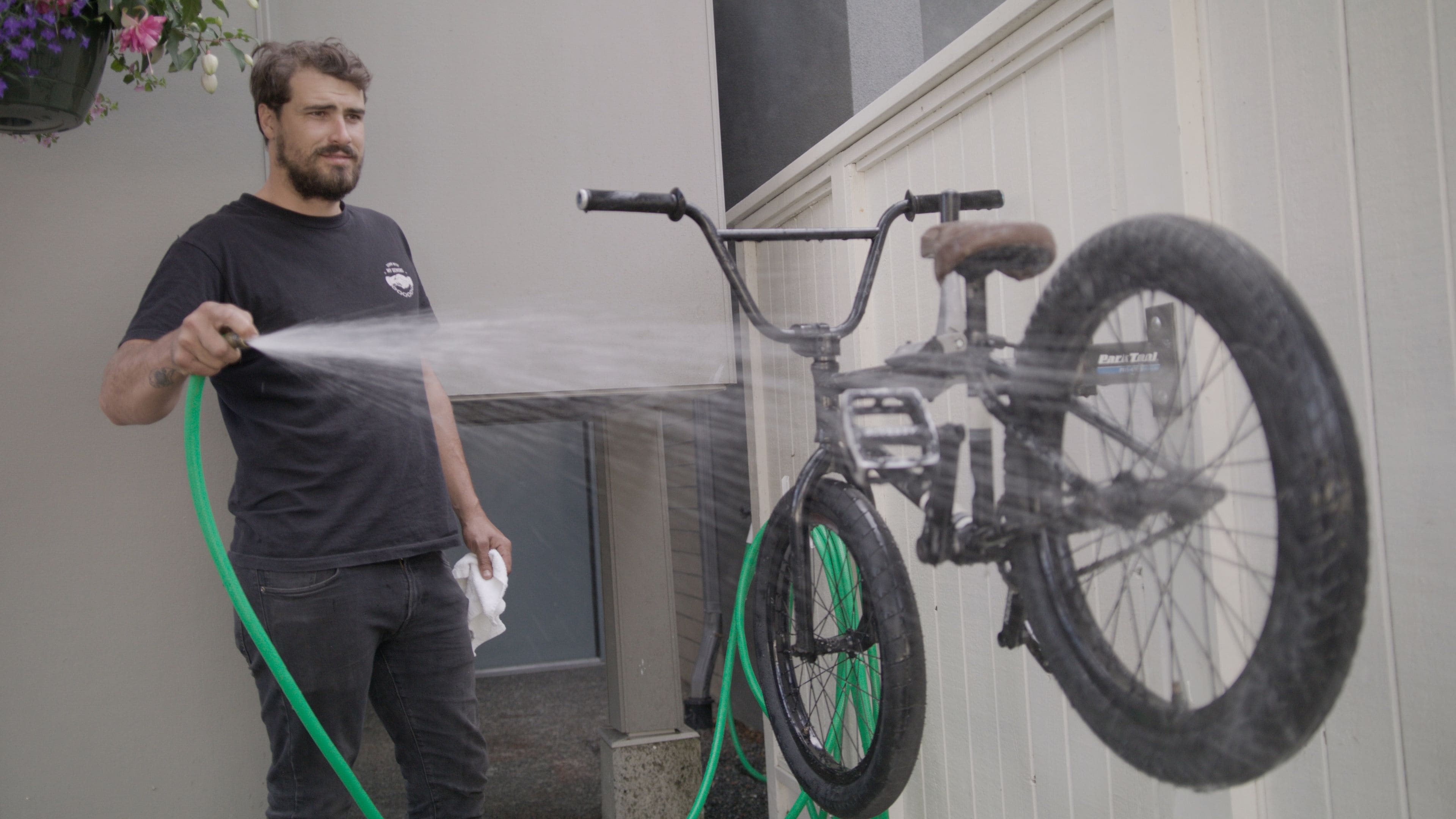 Una persona lava una bicicleta con una manguera.