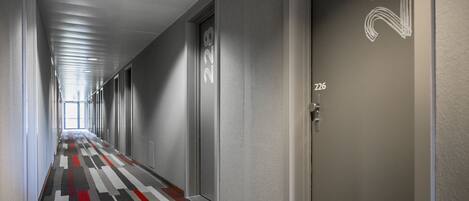 Un pasillo con puertas numeradas 222 y 226, un suelo con alfombra estampada e iluminación empotrada en el techo.