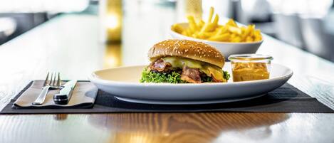 A meal with a burger, fries, and a small container of sauce on a table.