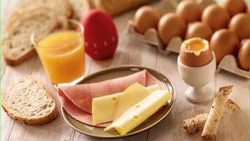 A breakfast setting with bread, eggs, cheese, and a glass of orange juice on a wooden table.