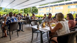 Un área de comedor al aire libre con mesas y sillas, rodeada por un toldo blanco.
