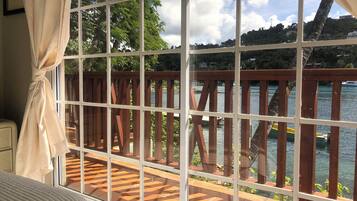 Una habitación con un ventanal grande que da a una terraza de madera y una masa de agua.