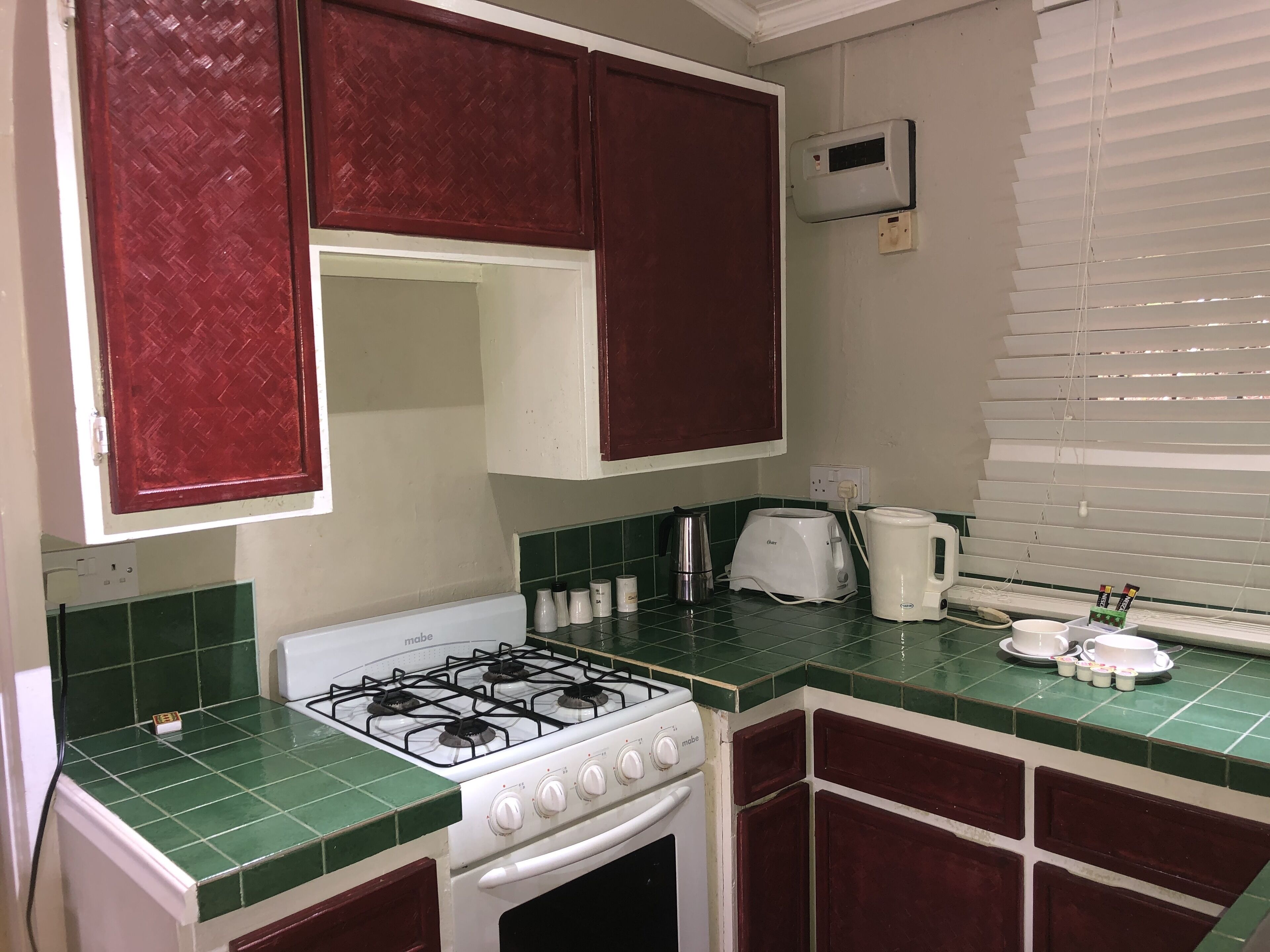 A compact kitchen with a gas stove, a coffee maker, and a toaster.