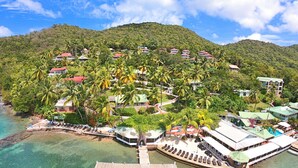 An aerial view of a resort with multiple buildings, a dock, and clear turquoise waters.