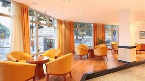 A hotel lobby with yellow chairs, a reception desk, and large windows. - Bristol (Buenos Aires)