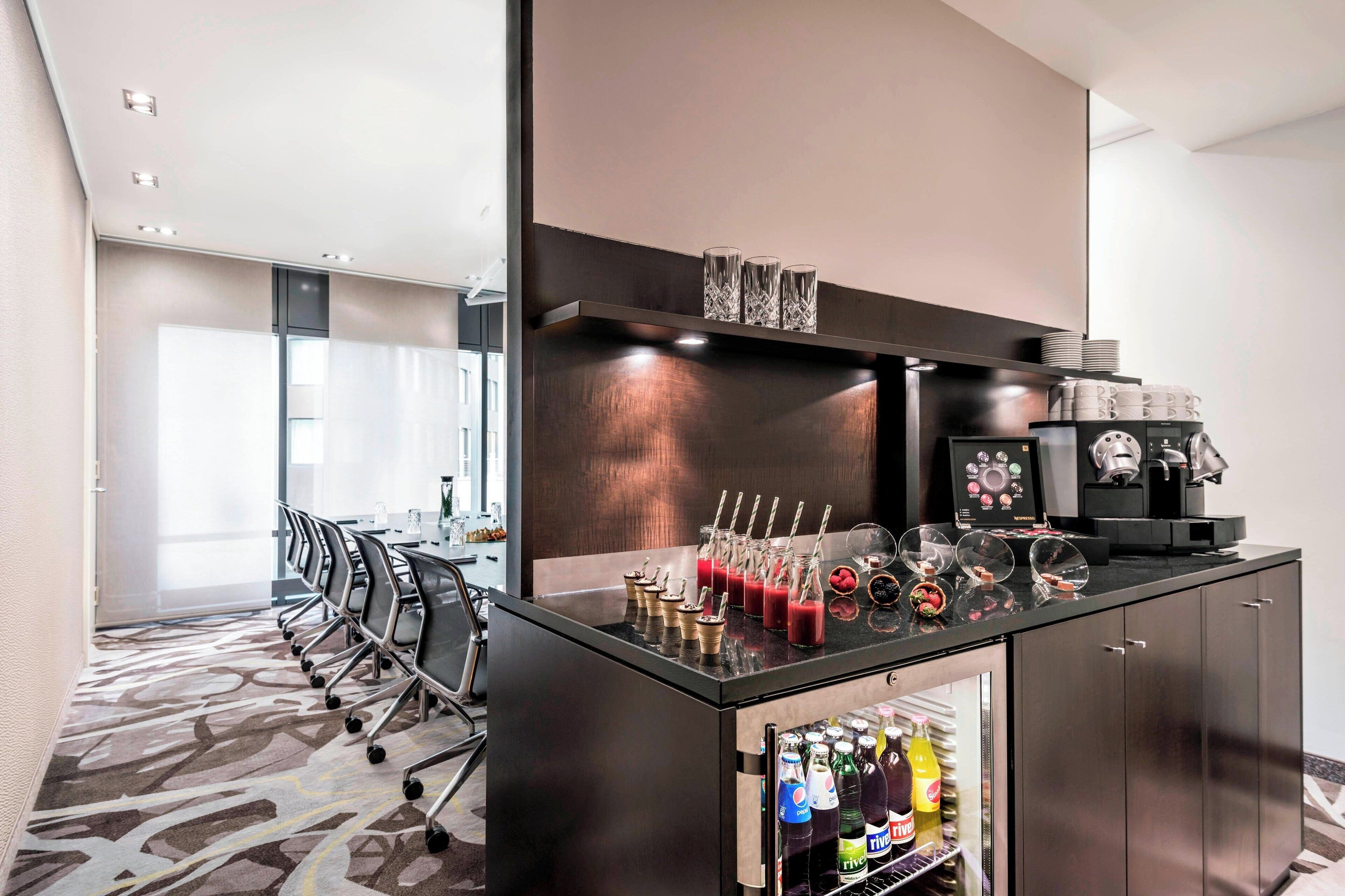 A modern bar area with a counter, glassware, and a refrigerator stocked with beverages.