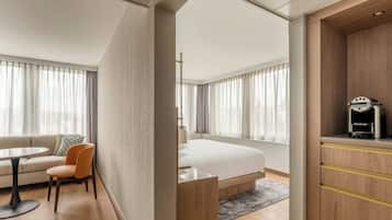 Ett modernt hotellrum med en säng, en soffa, ett matbord och en kaffemaskin.