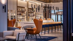Zona de bar moderna con asientos y barra, mostrando una variedad de botellas y copas.