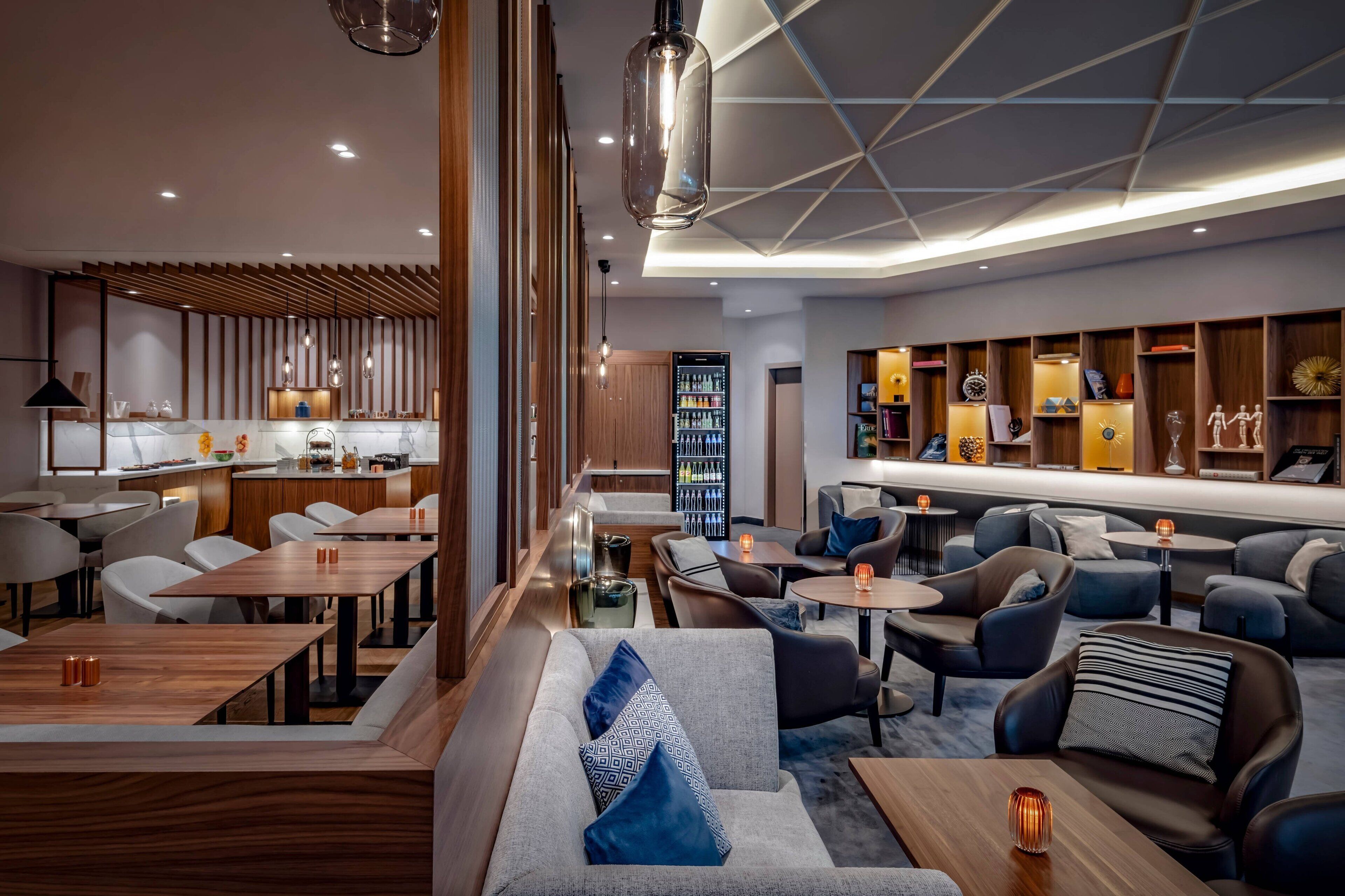 A modern hotel lobby with a dining area, seating arrangements, and a bar.