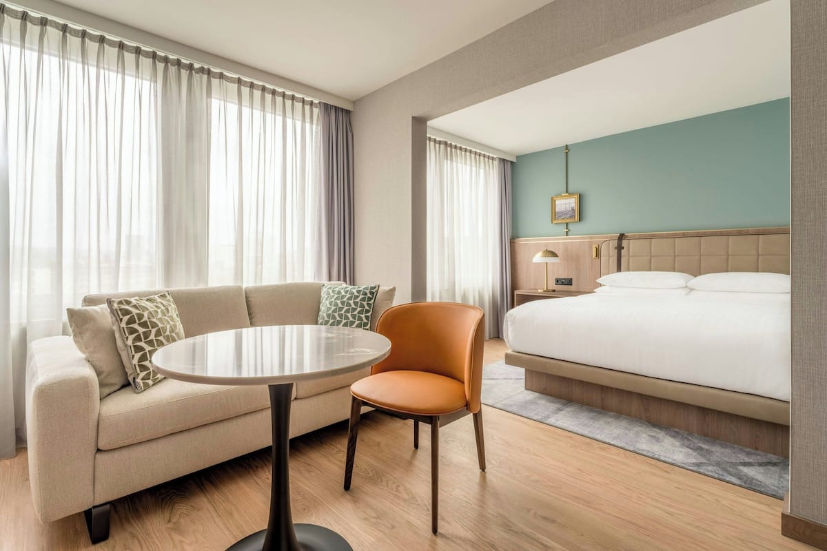 Hotellihuone, jossa on sänky, sohva, pyöreä pöytä ja tuoli.