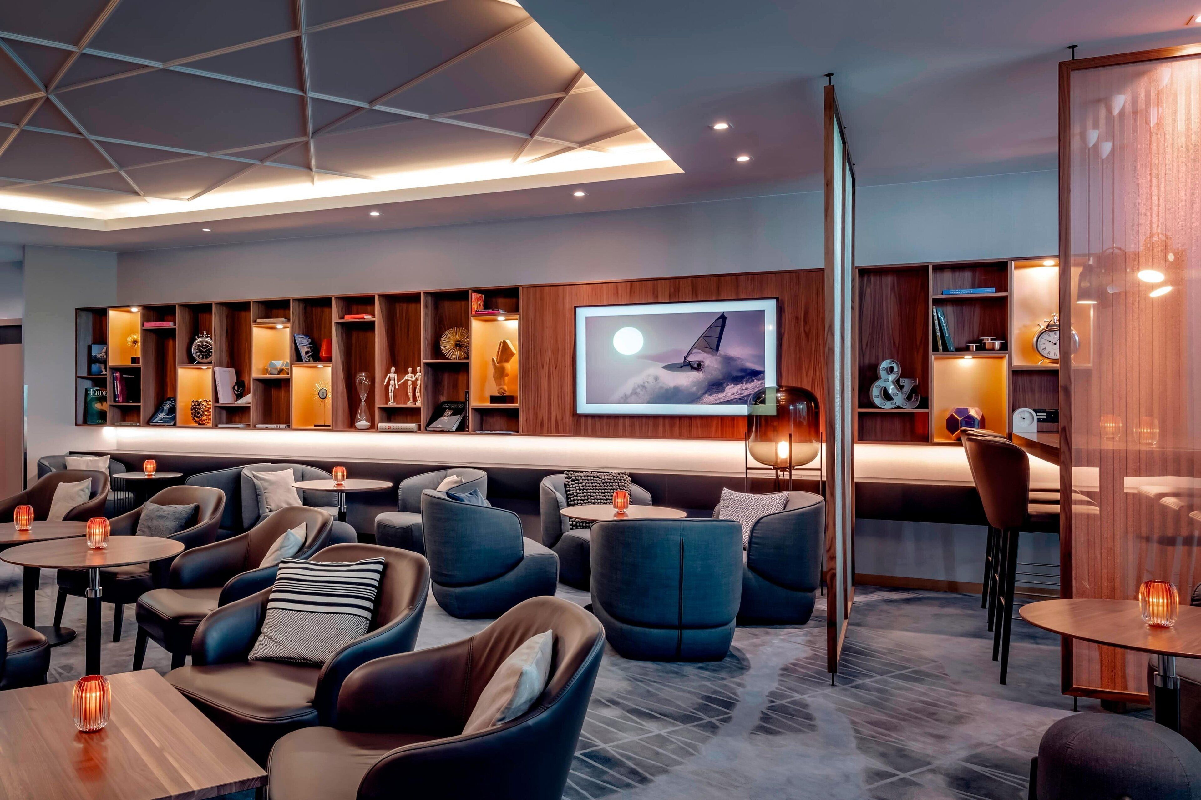 A modern lounge area with sofas, tables, and a large screen displaying a sailboat.