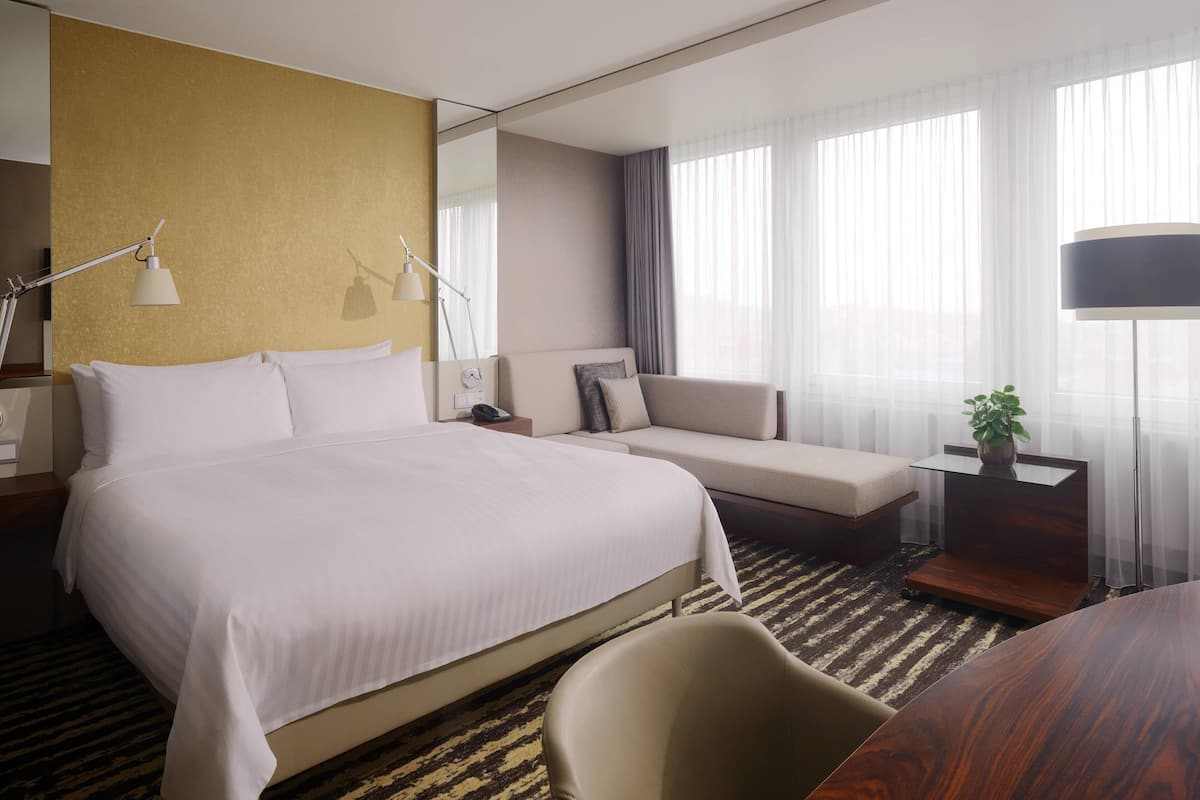 Hotellihuone, jossa on suuri sänky, sohva, työpöytä ja tuoli.