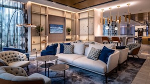 Una sala moderna con un sofá, sillones y una mesa de centro. Hay un comedor con sillas y una mesa.
