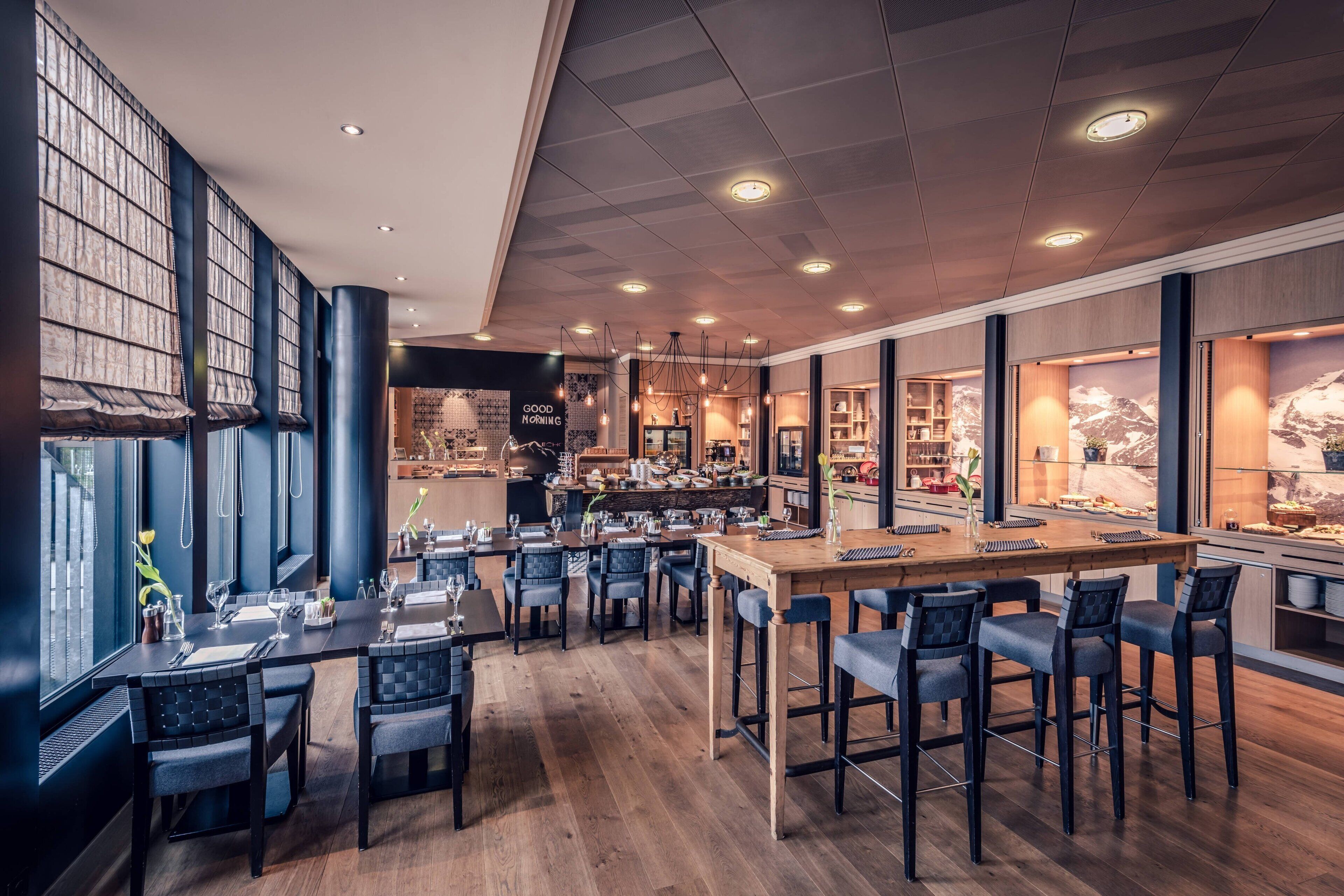 A modern restaurant with a bar area, wooden flooring, and large windows.
