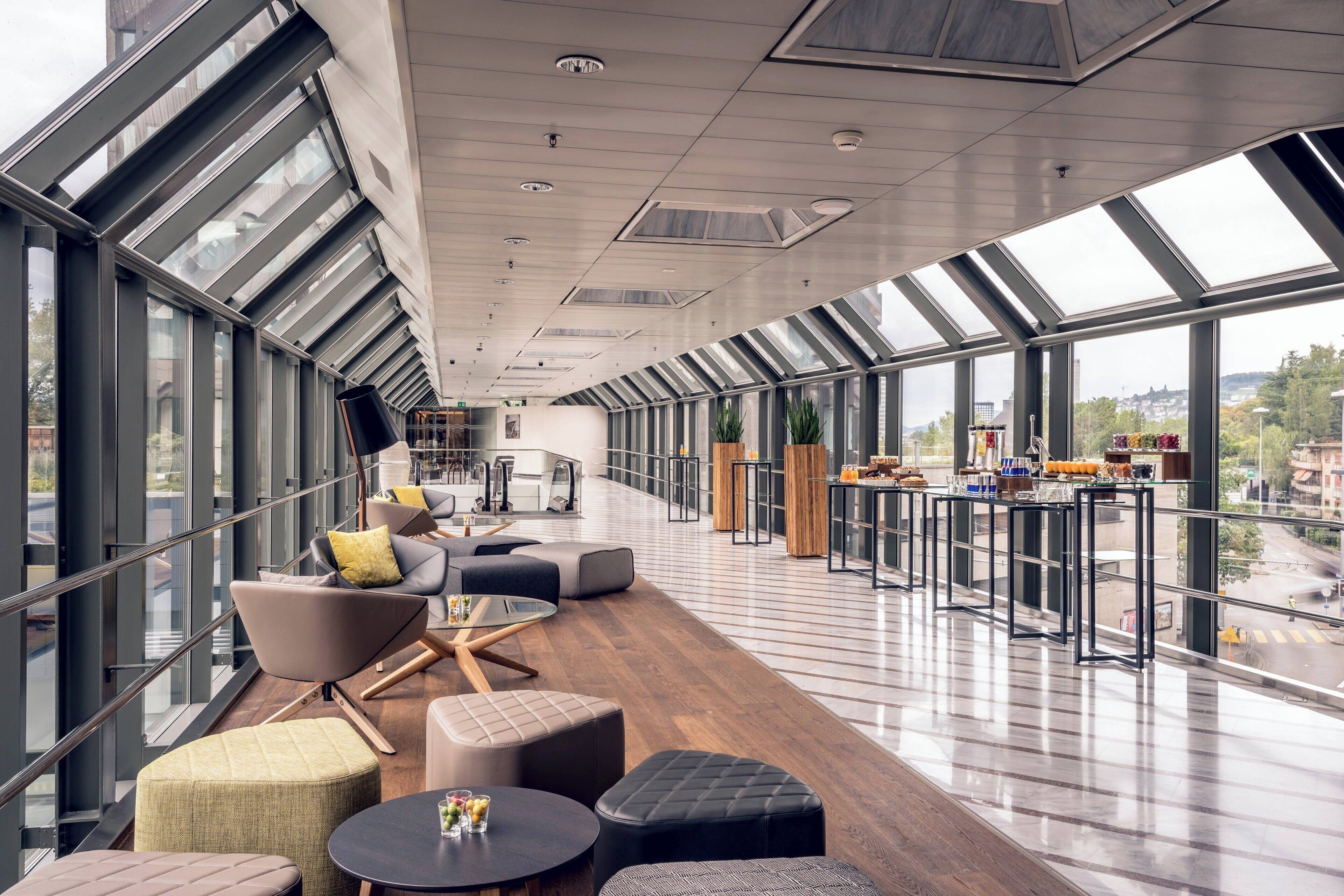 Een ruime, moderne lounge met hoge plafonds, grote ramen en comfortabele zitplaatsen.