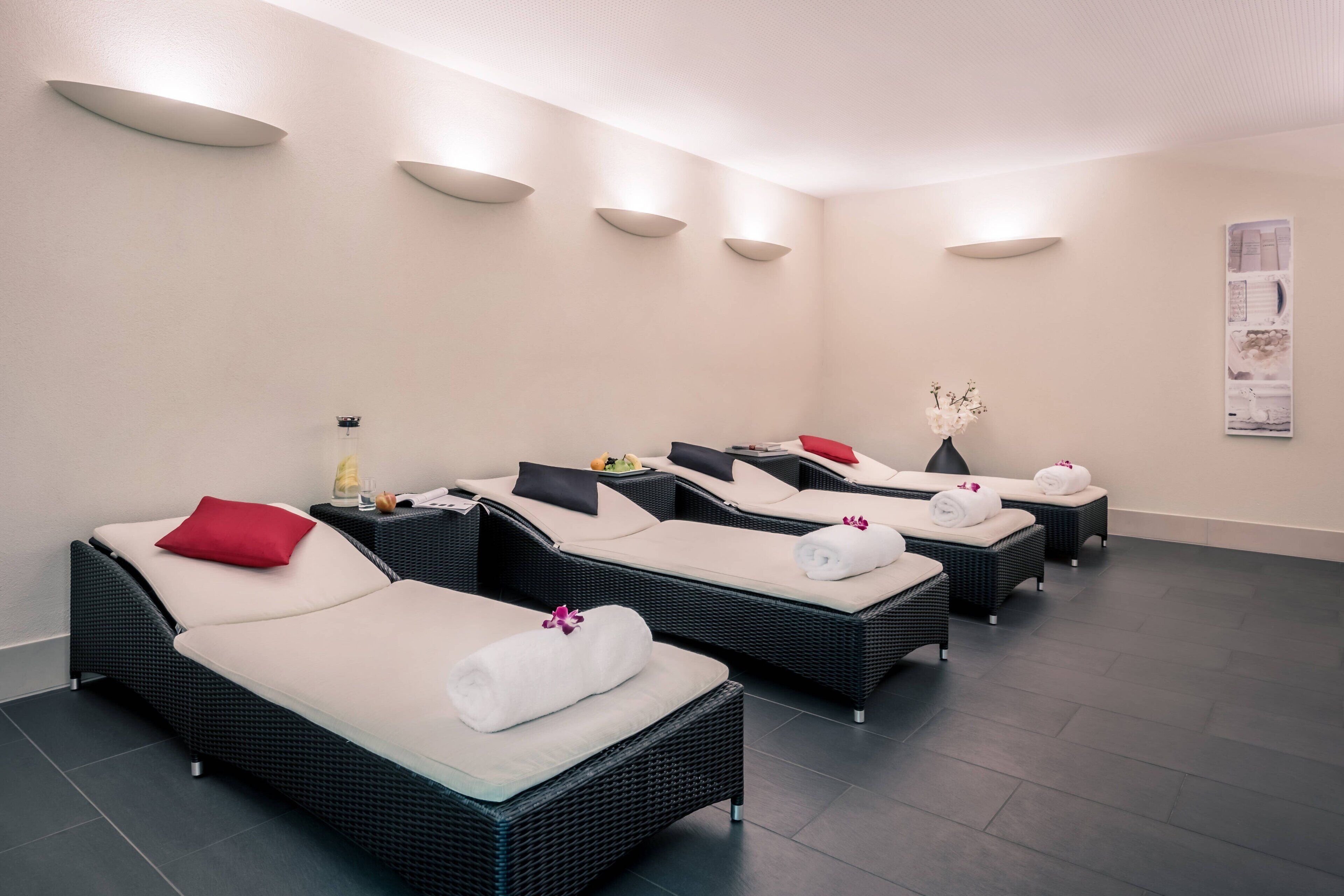 Un cuarto de spa con cuatro sillones reclinables, cada uno con una toalla y una flor.