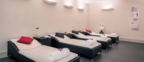 Un cuarto de spa con cuatro sillones reclinables, cada uno con una toalla y una flor.