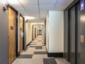 A hotel hallway with doors numbered 206 and 208, a checkered carpet, and a ceiling with recessed lighting. - ibis Paris Gennevilliers (Gennevilliers)