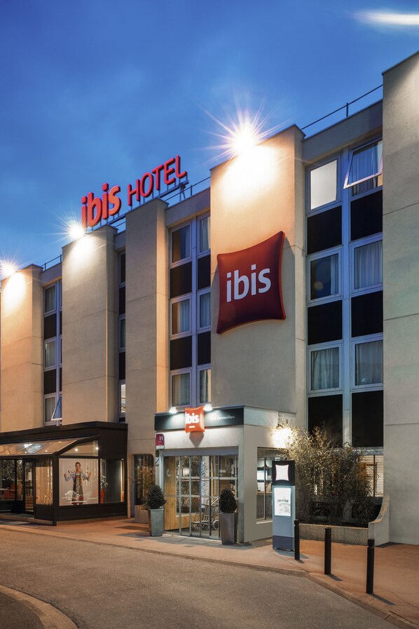 A hotel with a prominent 'Ibis Hotel' sign, a glass entrance, and a modern facade. - ibis Paris Gennevilliers (Gennevilliers)