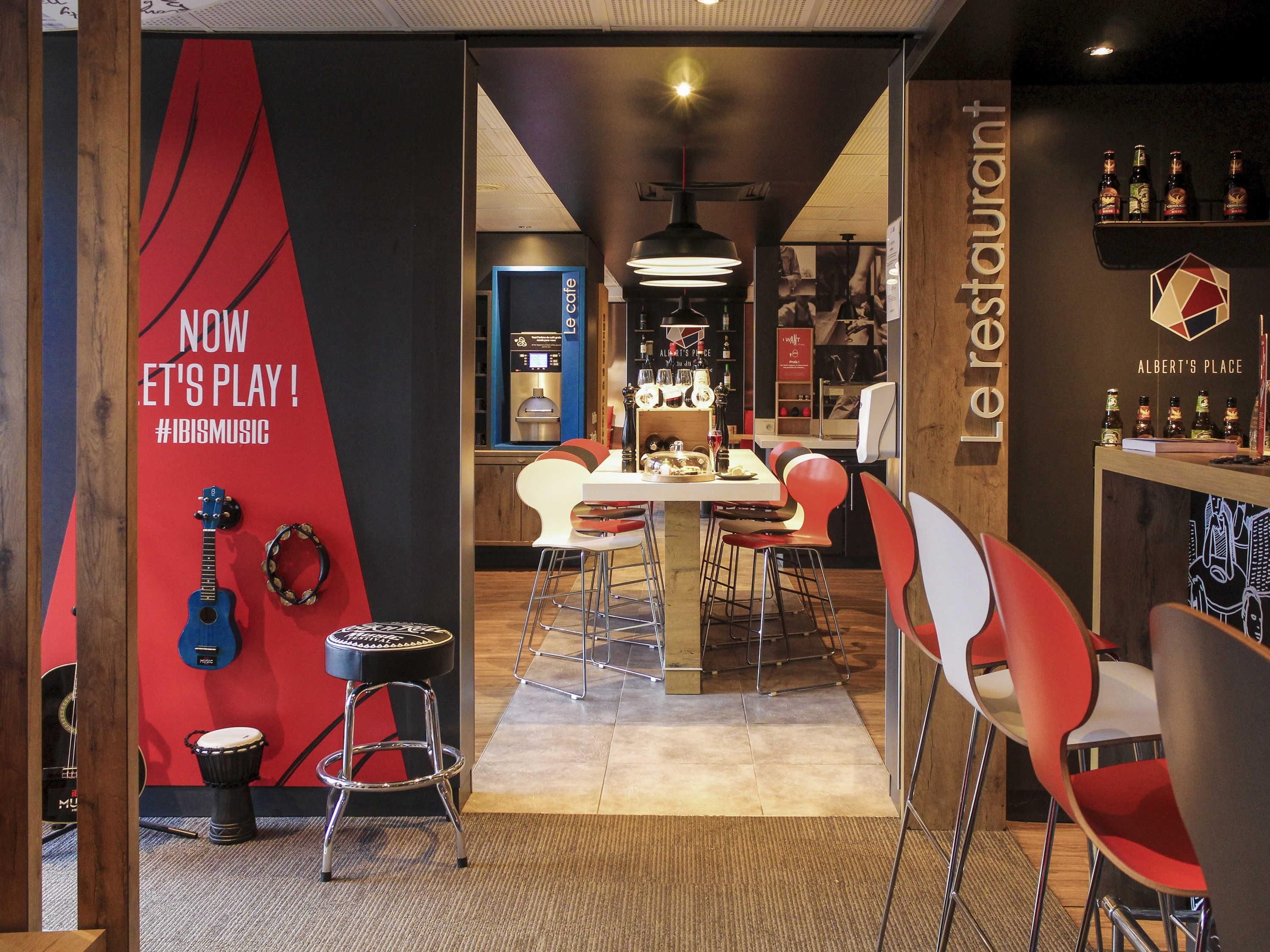 A restaurant interior with a red and black wall, a table with chairs, and a counter with bottles.