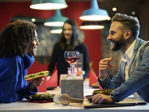 A restaurant setting with a table, food, and a glass of red wine. - ibis Paris Gennevilliers (Gennevilliers)