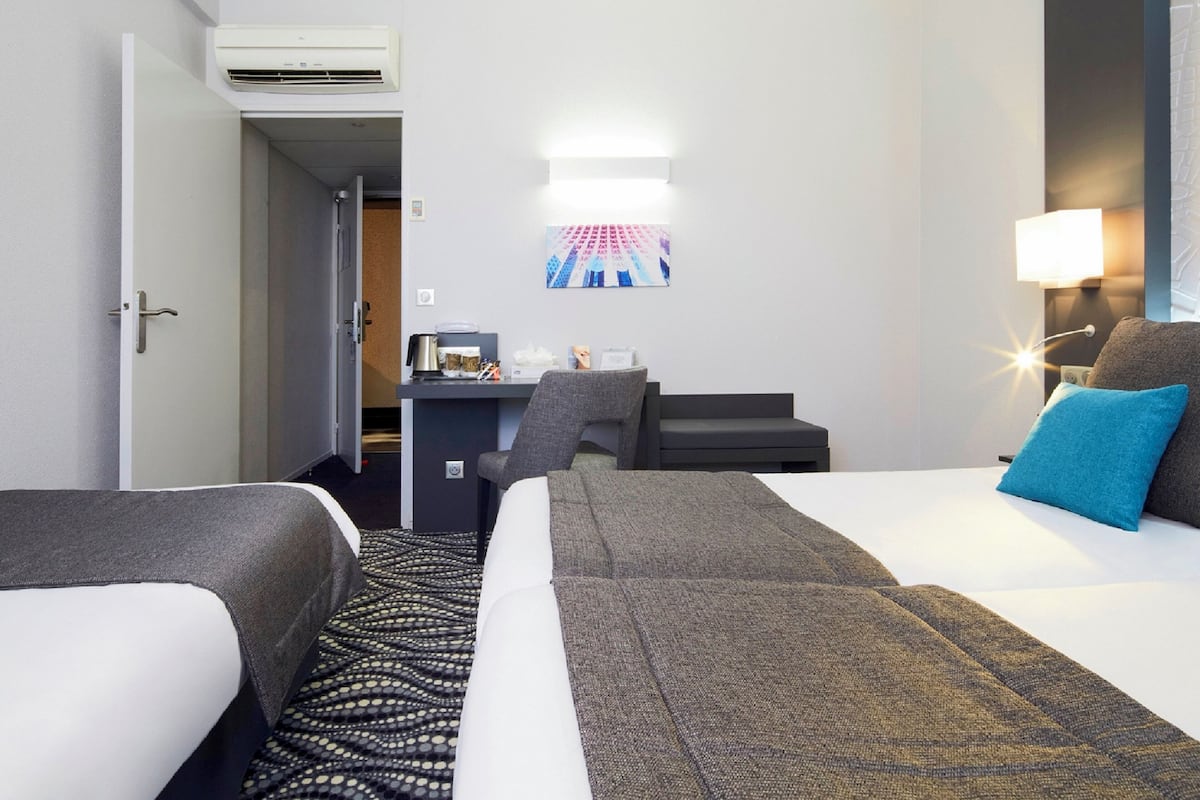 Een hotelkamer met twee bedden, een bureau, een stoel, een lamp en een airconditioning.