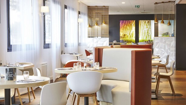 A modern restaurant interior with round tables, white chairs, and a vibrant abstract mural on the wall. - Hôtel Kyriad Paris Bezons - La Défense (Bezons)