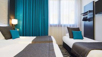 A hotel room with two beds, a large window with sheer curtains, a wall-mounted TV, and a patterned rug.