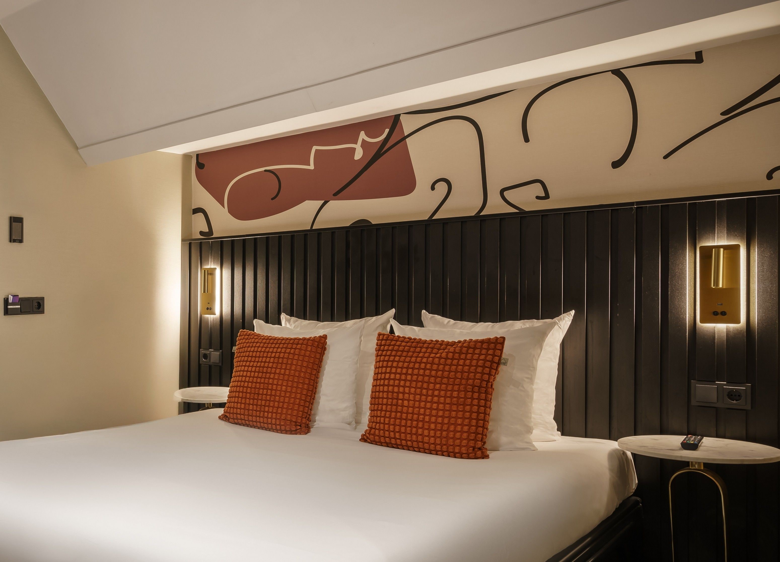 Ein Hotelzimmer mit einem großen Bett, zwei Kissen, einem Nachttisch und einer Wandleuchte.